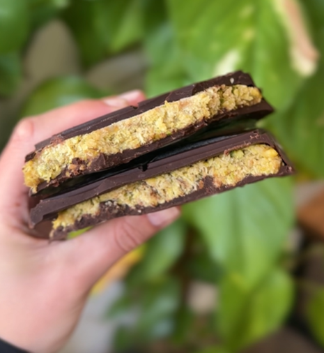A chocolate bar cut open to show a pistachio and kataifi filling