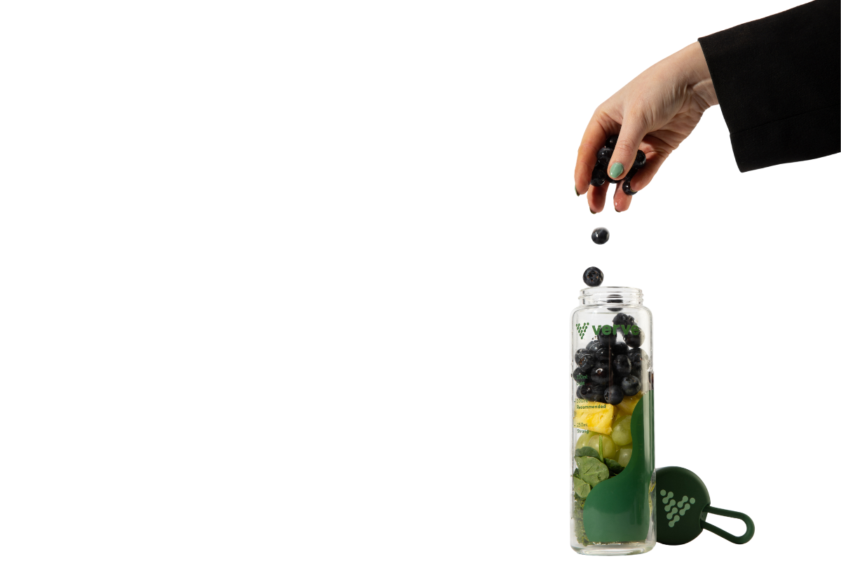 hand dropping fruit into bottle filled with fruit