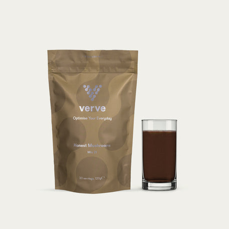 A pouch of Verve Honest Mushrooms Mix 21 powder next to a glass filled with a dark brown drink.