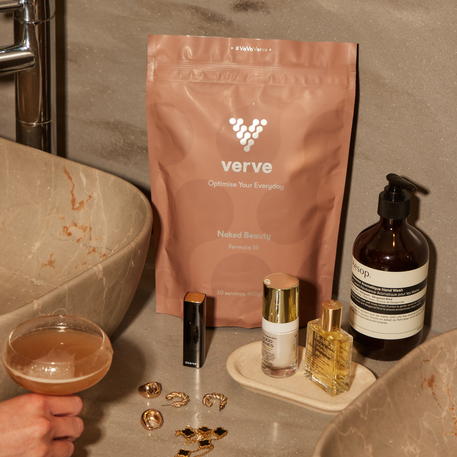 Verve Naked Beauty Collagen pouch displayed on a bathroom counter alongside luxury skincare, gold jewellery, and a cocktail, creating a premium self-care scene.
